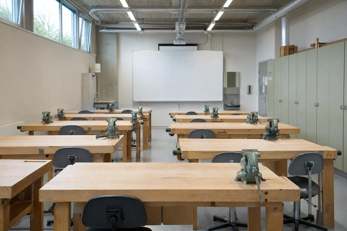 Salle de cours professionnels avec établis vides et matériel pédagogique aligné