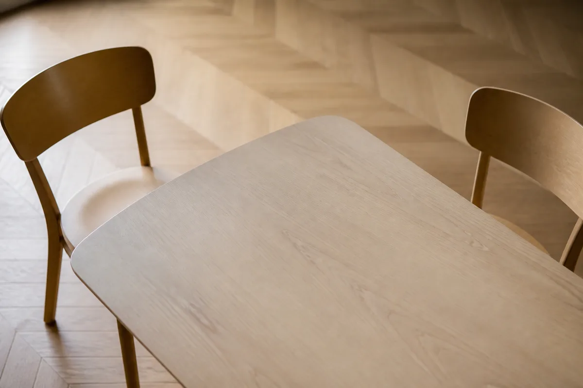 Table de réunion en bois clair et chaises vides dans un bureau suisse baigné de lumière naturelle