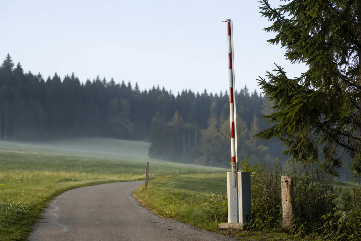 Barrière de poste-frontière relevée sur une route de campagne suisse au petit matin